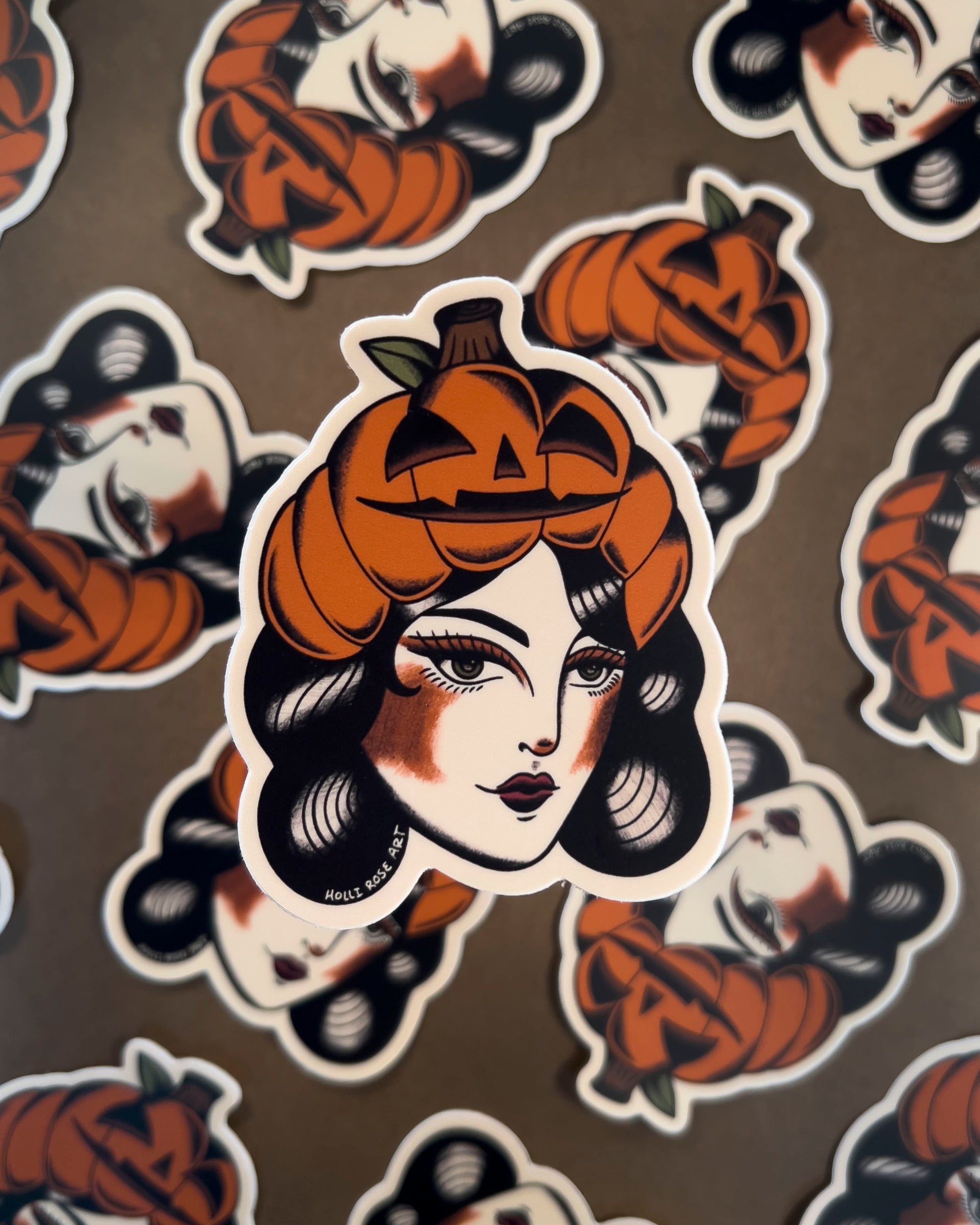 Sticker of a woman's face with a pumpkin on her head on a brown background.