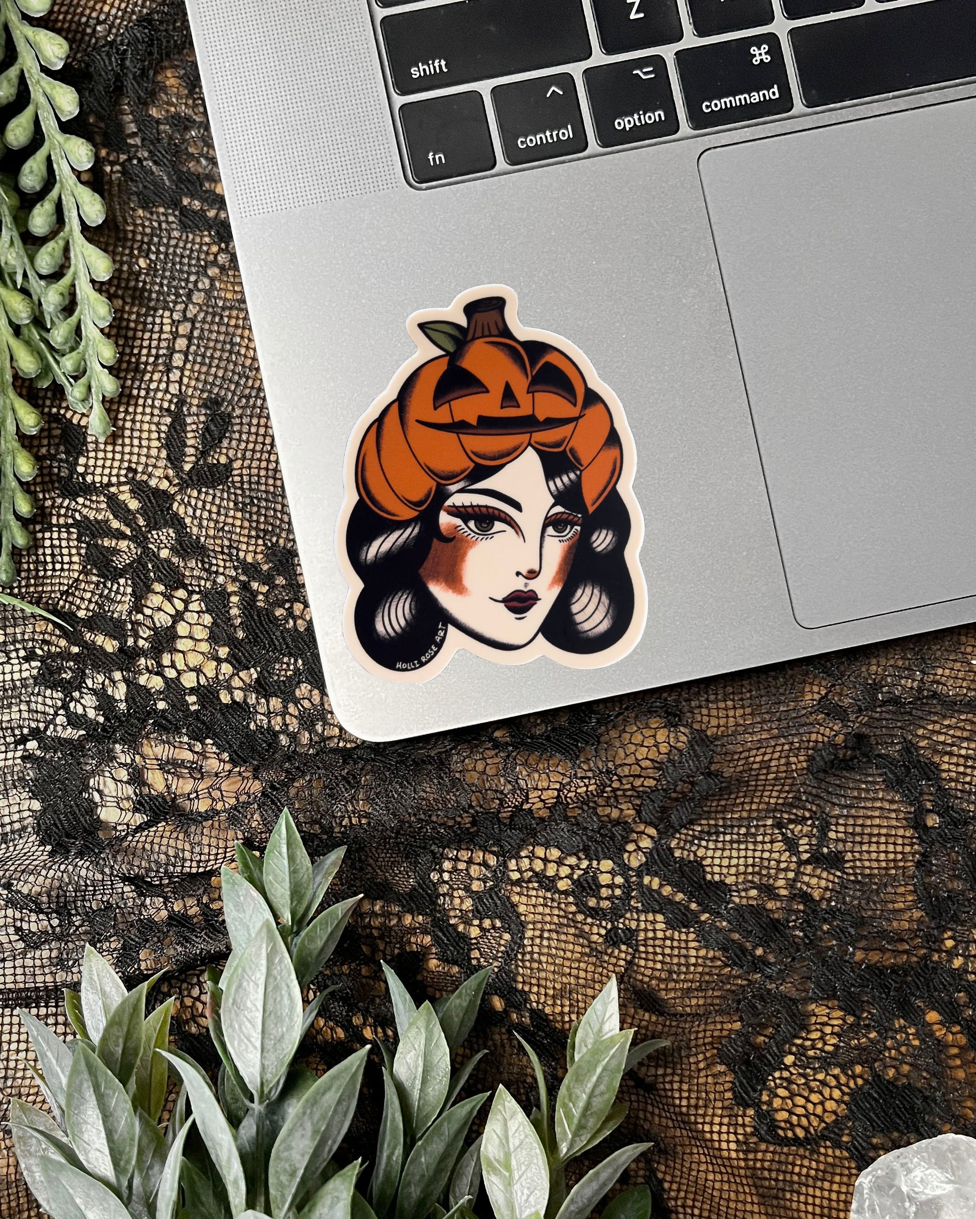 Sticker of a woman's face with a pumpkin on her head on a brown background.
