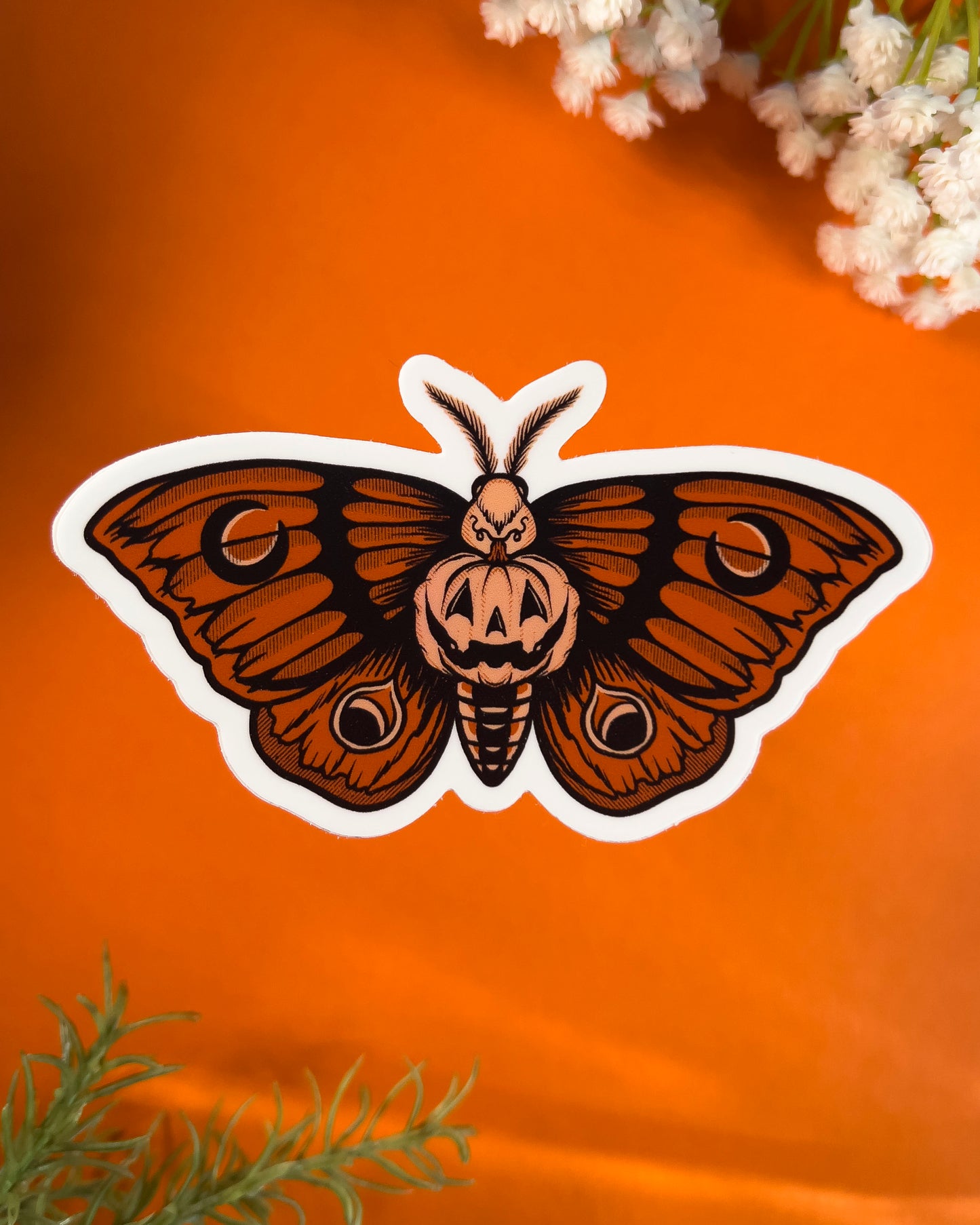 sticker of an orange moth with a pumpkin in the center