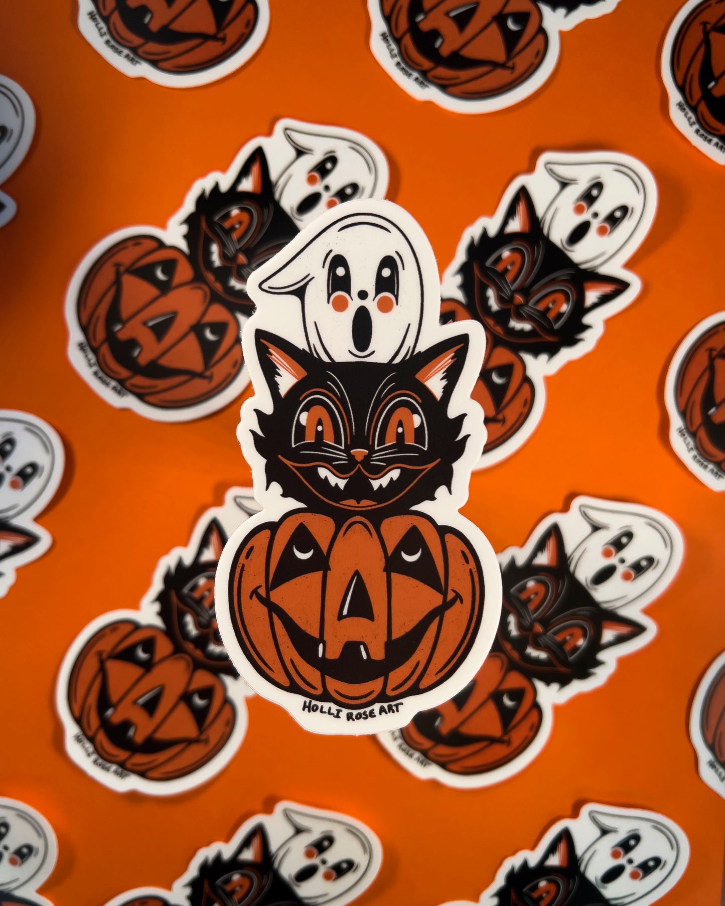 Halloween-themed sticker with a cat, ghost, and pumpkin on an orange background.