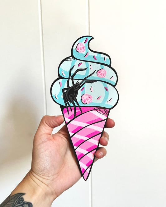 Hand holding a colorful ice cream cone-shaped object with pink and blue design.