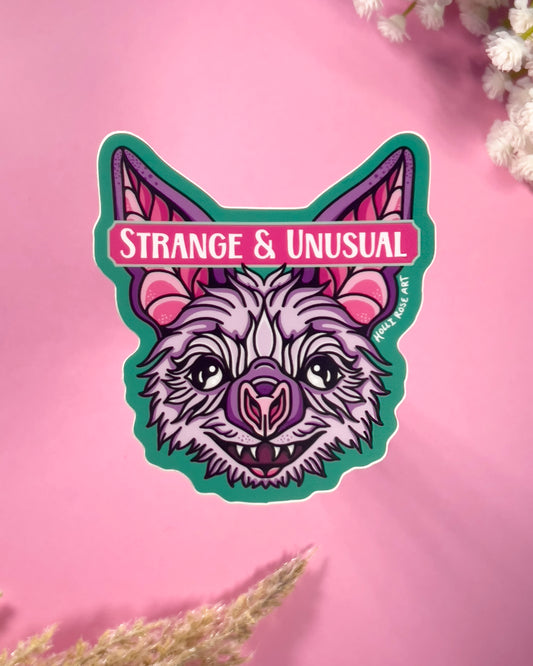 Sticker with a stylized bat design and 'Strange & Unusual' text on a pink background.