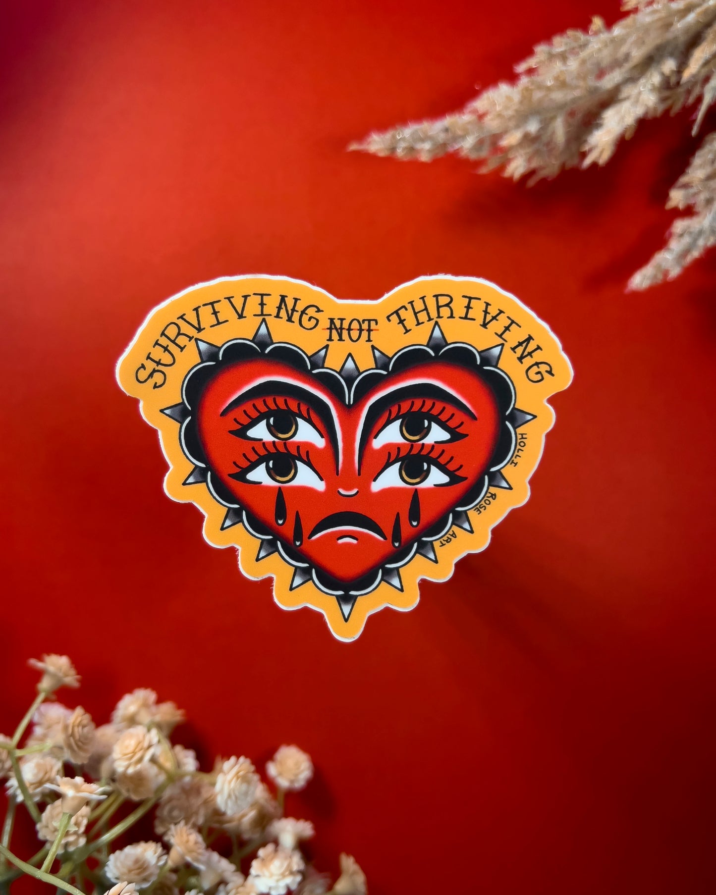 heart sticker with eyes that says "surviving not thriving"