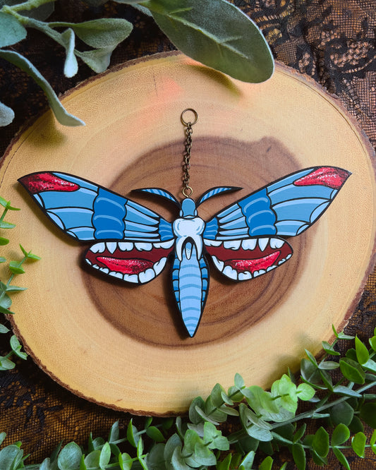 hand painted moth with a tooth in the center and mouths on the bottom wings