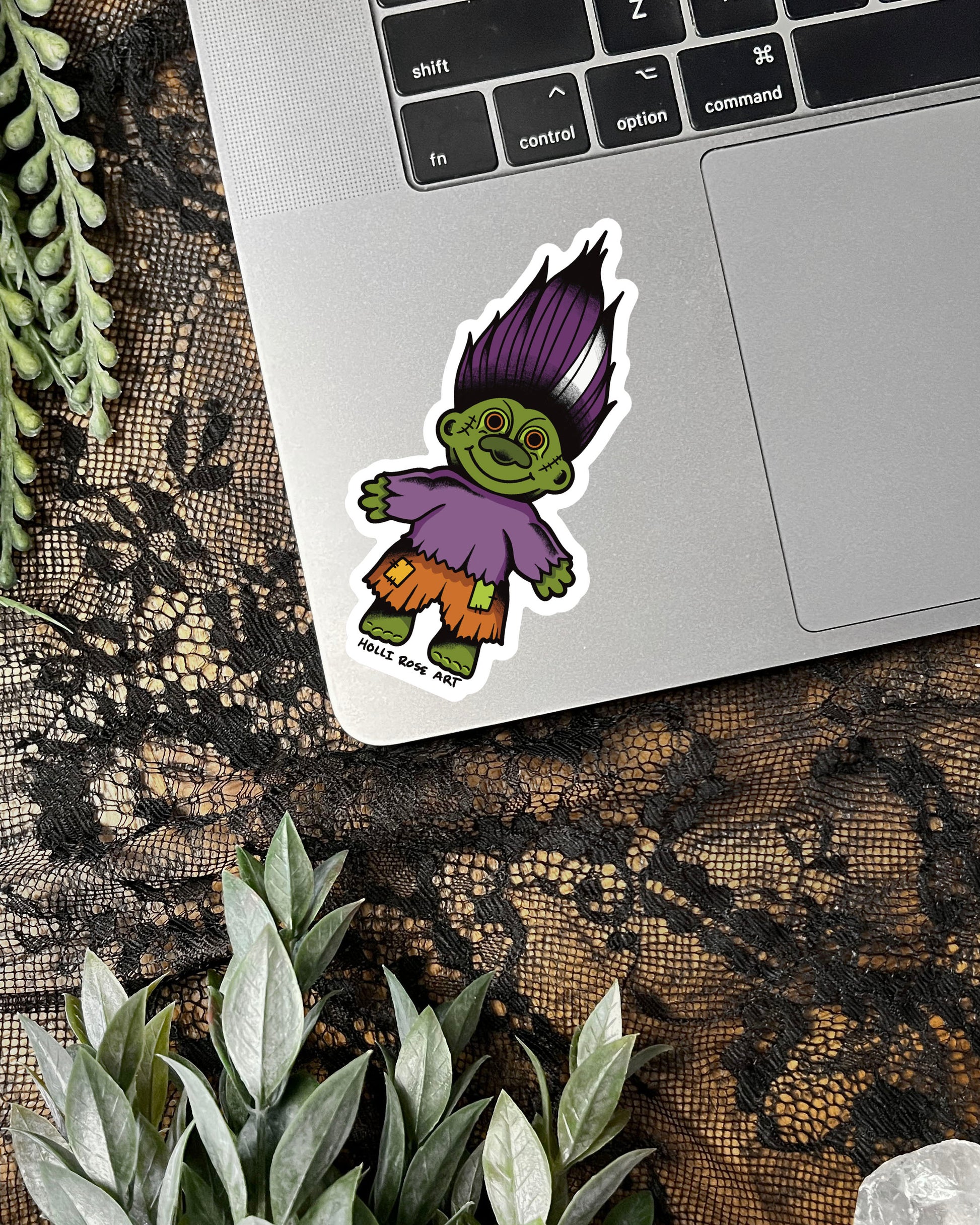 Sticker of a green troll with purple hair on a laptop