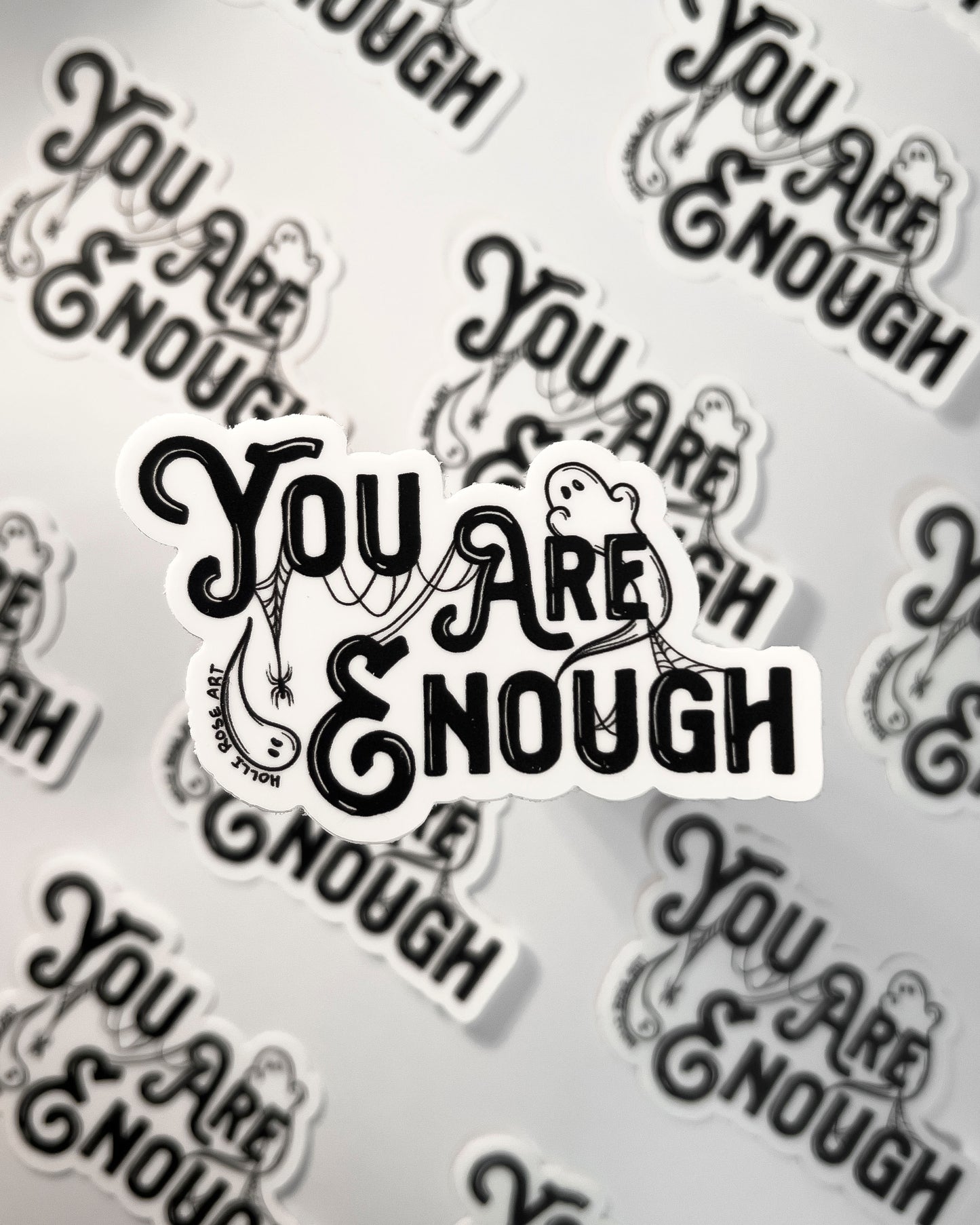 a sticker saying you are enough with ghosts