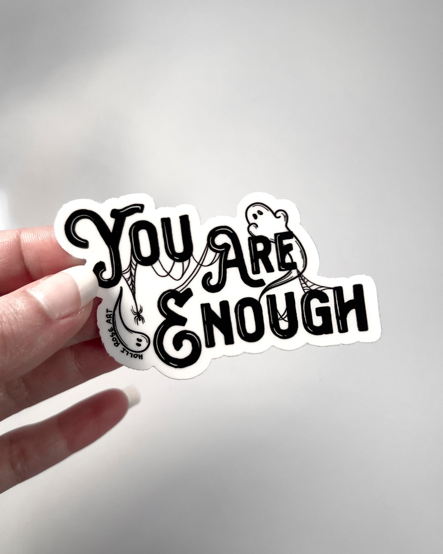 a sticker saying you are enough with ghosts